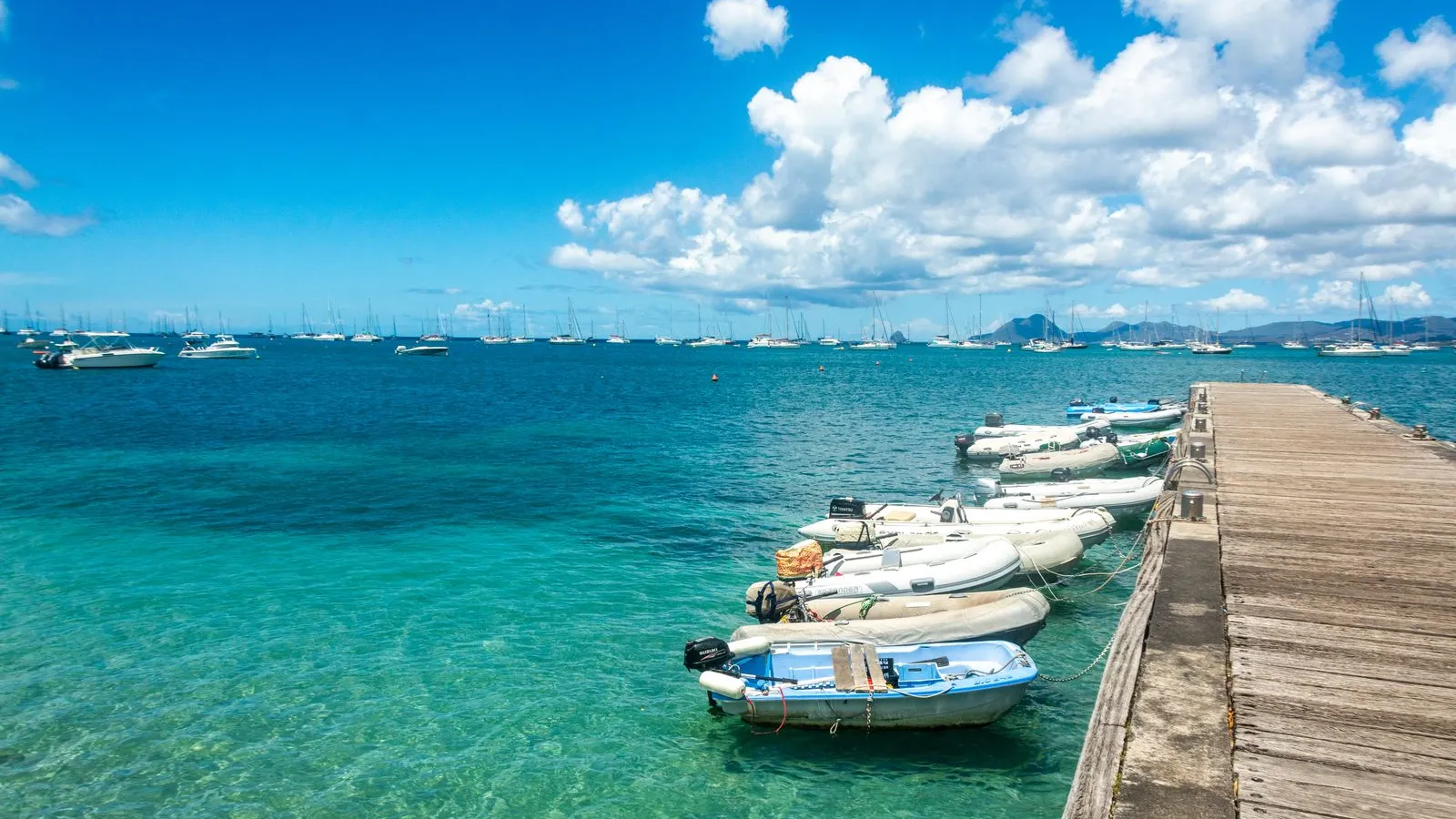 Ponton sur une eau turquoise avec le Rocher du Diamant à l'horizon
