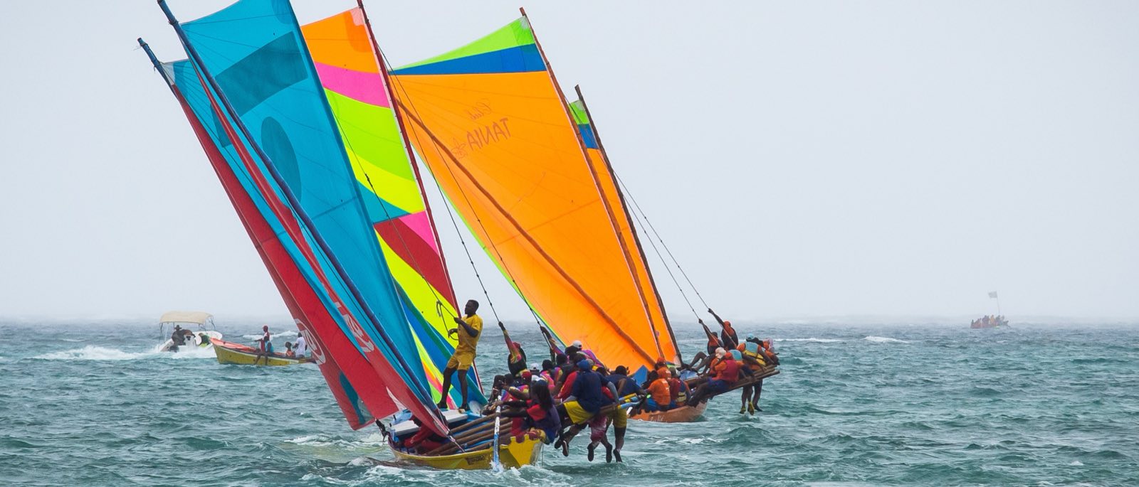 Deux yoles rondes aux voiles multicolores en pleine course, équipiers en rappel sur les bois